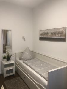 Bett in einem weißen Zimmer mit einem Bild an der Wand in der Unterkunft Hotellerie Gasthaus Schubert in Garbsen