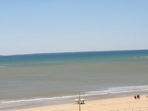 una spiaggia con persone in piedi sulla sabbia e sull'oceano di Studio alcôve, vue mer, 4 personnes, Saint Jean de Monts a Saint-Jean-de-Monts