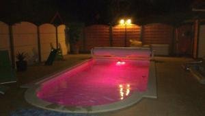 una piscina con luces rosas en un patio trasero por la noche en LA MAISON DES HIPPOCAMPES, en La Teste-de-Buch