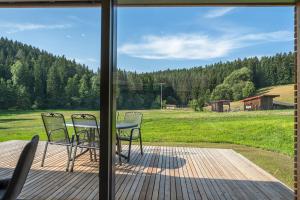 a table and chairs on a deck with a view of a field at Modul Häuser Maurer in Georgenberg