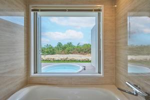 a bath room with a tub and a window at Watermark Hotel Okinawa Miyakojima in Miyako Island +38 photos