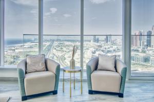 two chairs and a table in a room with windows at GuestReady - Sea view apt overlooking The Palm in Dubai
