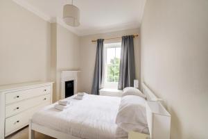 een witte slaapkamer met een bed en een raam bij GuestReady - Amazing apt near The Meadows in Edinburgh