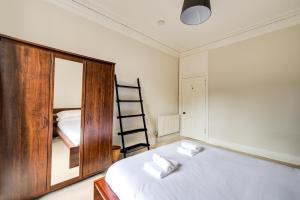 een slaapkamer met een bed met een spiegel en een ladder bij GuestReady - Amazing apt near The Meadows in Edinburgh
