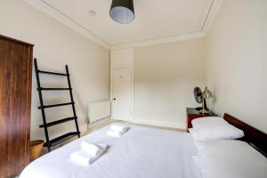 een slaapkamer met 2 bedden met witte lakens en een ladder bij GuestReady - Amazing apt near The Meadows in Edinburgh