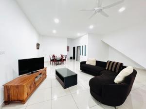 ein Wohnzimmer mit einem schwarzen Sofa und einem TV in der Unterkunft SingBeach holiday house in Mersing