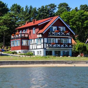 a red and white house next to the water at Prie Mariu in Nida