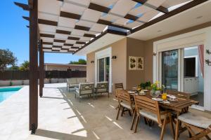 a patio with a table and chairs and a pool at Cypress View Boutique Villa in Asgourou