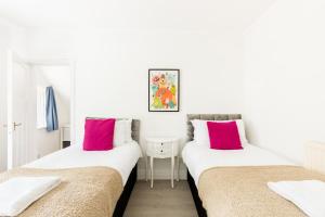 2 camas en una habitación blanca con almohadas rosas en Beautiful 6 bedroom house for 15 guests next to Edgbaston Stadium en Birmingham