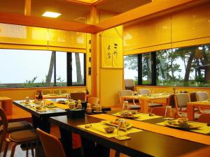 a dining room with tables and chairs and windows at Hotel Castle Inn Ise Meotoiwa in Ise