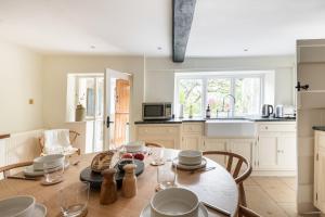 a kitchen with a table and chairs in a room at Architect Designed Cosy Cotswold Stone Cottage in Quenington