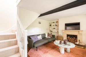 a living room with a couch and a fireplace at Architect Designed Cosy Cotswold Stone Cottage in Quenington