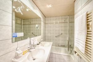 un bagno con un lavandino, una vasca e uno specchio di Hotel Simi a Zermatt