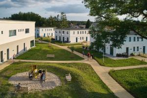 eine Gruppe weißer Gebäude mit Menschen, die durch einen Park gehen in der Unterkunft TUI SUNEO Kinderresort Usedom in Trassenheide