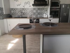 2 copas de vino en una mesa de madera en una cocina en Chez Alex et Sophie, en Louzac - Saint-André