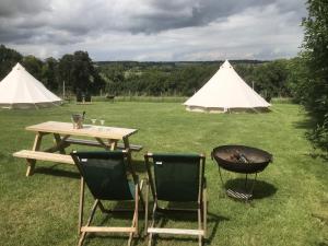 a table and two chairs and a grill and tents at Home Farm Radnage Glamping Bell Tent 7, with Log Burner and Fire Pit in High Wycombe