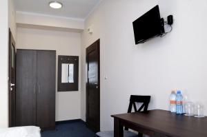 a room with a table and a television on a wall at Baza Hotelowa Bobrowiecka 9 in Warsaw