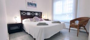 una camera con un letto bianco, una sedia e una finestra di Laguna Beach - Coral Side a Torrox Costa Altre 17 foto