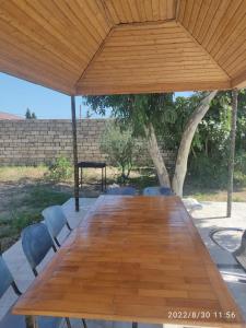 Cozy home for leisure في باكو: طاولة وكراسي خشبية طويلة تحت جناح