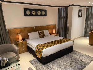 1 dormitorio con 1 cama grande y 1 silla en Airport West Hotel en Accra