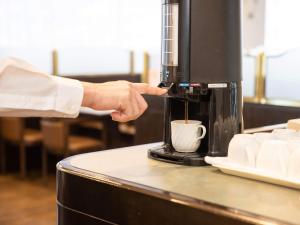 a person is pouring coffee into a coffee machine at Hotel Castle Inn Suzuka in Suzuka
