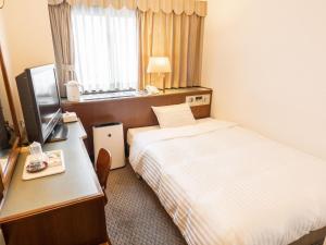 鈴鹿市にあるHotel Castle Inn Suzukaのベッド、デスク、テレビが備わるホテルルームです。