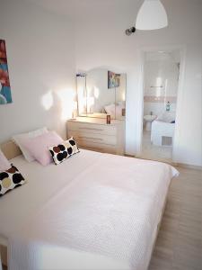 een witte slaapkamer met 2 bedden en een spiegel bij Apartman Helena in Gradac