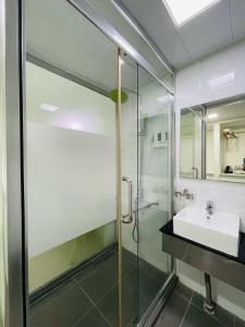 a bathroom with a glass shower and a sink at Green Apple Boutique Hotel in Kota Kinabalu