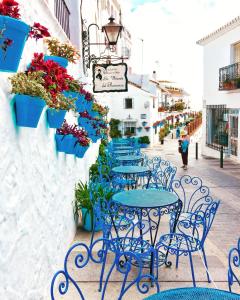 1 Mijas Apartment في ميخاس: صف من الطاولات والكراسي الزرقاء على شارع