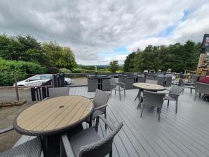 a wooden deck with tables and chairs on it at Sashas retreat in Gisburn
