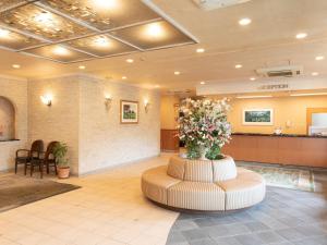 un vestíbulo con una sala de espera con un arreglo floral en el centro en Hotel Castle Inn Suzuka Chuo, en Suzuka