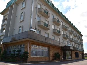 a large white building with windows on a street at Hotel Castle Inn Suzuka Chuo in Suzuka