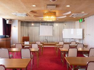 a classroom with tables and chairs and a projection screen at Hotel Castle Inn Yokkaichi in Yokkaichi