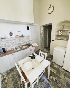 una cucina con tavolo e sedie bianchi e orologio di Appartamento Luxury a Massafra