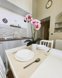 un tavolo con piatti bianchi e un vaso con fiori rosa di Appartamento Luxury a Massafra