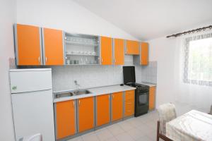 布羅達里卡的住宿－Apartments with a parking space Brodarica, Sibenik - 6313，厨房配有橙色橱柜和白色冰箱