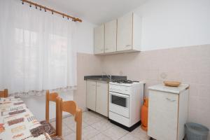 a kitchen with a white stove top oven next to a table at Apartments by the sea Metajna, Pag - 6352 in Metajna