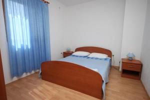 a bedroom with a bed and a window with blue curtains at Apartments by the sea Petrcane, Zadar - 6269 in Petrcane
