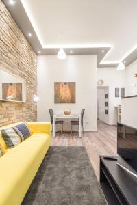 ein Wohnzimmer mit einem gelben Sofa und einem Tisch in der Unterkunft Venus Apartments - Almassy Park in Budapest
