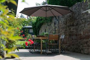 a table and chairs under an umbrella in a garden at Gemütliches Fachwerkhaus im Herzen Nideggens in Nideggen