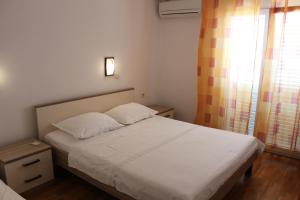 a small bedroom with a white bed and a window at Apartments with parking space Kustici, Pag - 6287 in Kustići