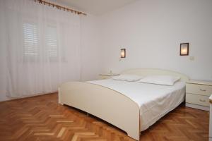a white bedroom with a white bed and a wooden floor at Apartments with parking space Kustici, Pag - 6287 in Kustići