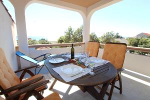 a table with a bottle of wine and glasses on a balcony at Apartments and rooms with parking space Mandre, Pag - 6309 in Kolan