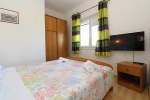 een slaapkamer met een bed en een flatscreen-tv bij Apartments and rooms with parking space Mandre, Pag - 6309 in Kolan