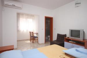 a bedroom with a bed and a tv and a table at Apartments and rooms with parking space Novalja, Pag - 6341 in Novalja