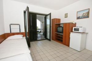 a small room with a bed and a microwave at Seaside apartments with a swimming pool Potocnica, Pag - 6407 in Borovići