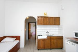 a kitchen with wooden cabinets and a sink at Seaside apartments with a swimming pool Potocnica, Pag - 6407 in Borovići