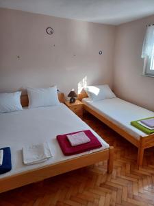 Duas camas num quarto com paredes brancas e pisos em madeira em Apartments with a parking space Pag - 6325 em Pag