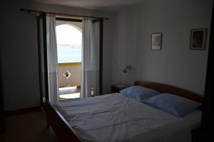 ein Schlafzimmer mit einem Bett und einem Fenster mit Blick auf das Meer in der Unterkunft Apartments by the sea Kustici, Pag - 6335 in Zubovići