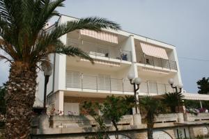 a building with a palm tree in front of it at Apartments with a parking space Novalja, Pag - 6398 in Novalja